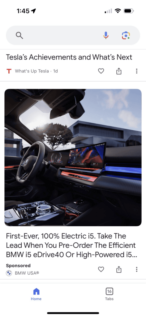 A mobile screenshot of a Google Discovery Ad for a BMW electric vehicle. There is a photo of the interior of a BMW vehicle showing the steering wheel, windscreen, and a large curved digital display screen. Below the photo is a long, truncated headline that begins: “First-Ever, 100% Electric i5.” The image is labeled “Sponsored”.