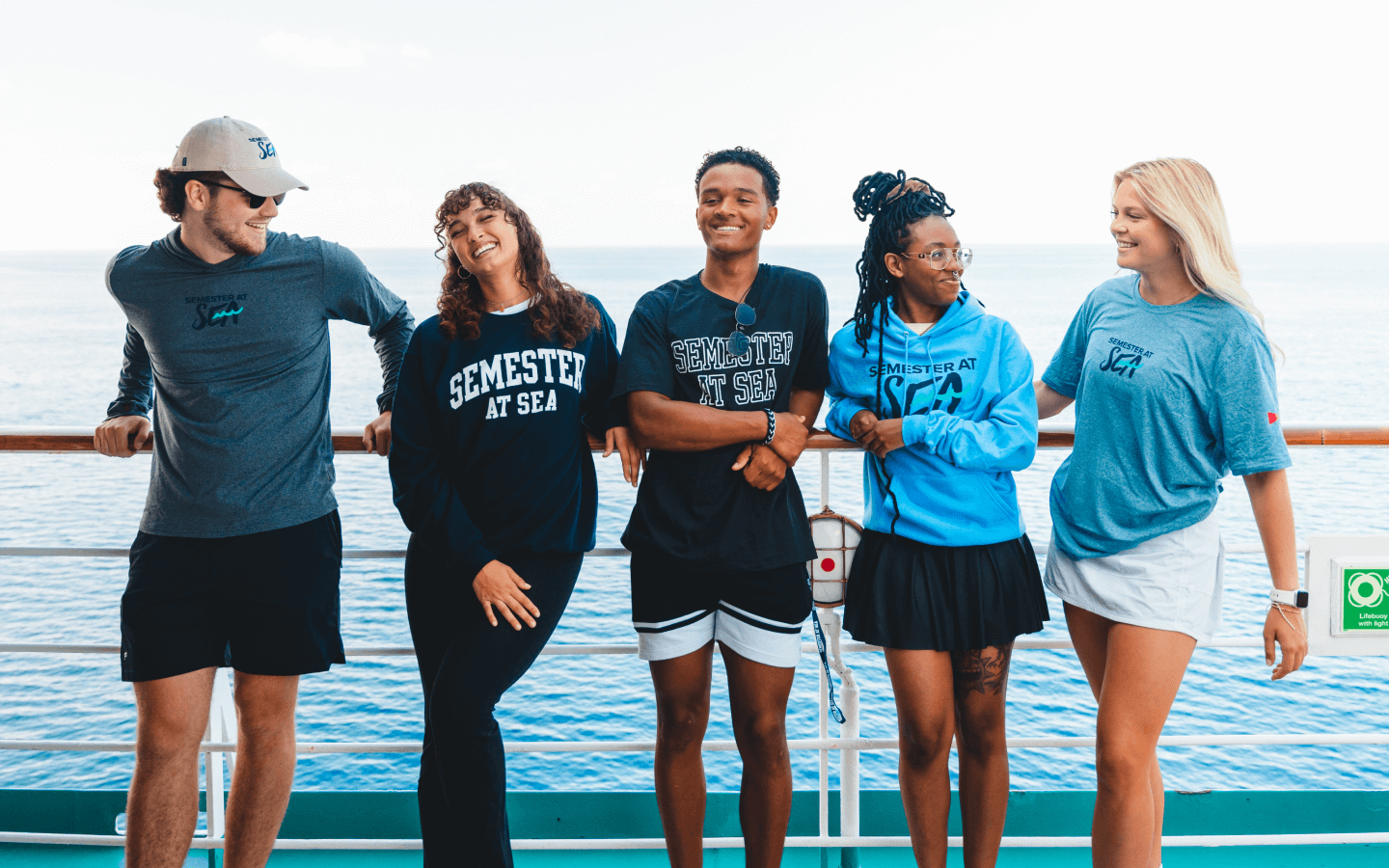 Semester at Sea students leaning against a rail of a ship on the ocean.